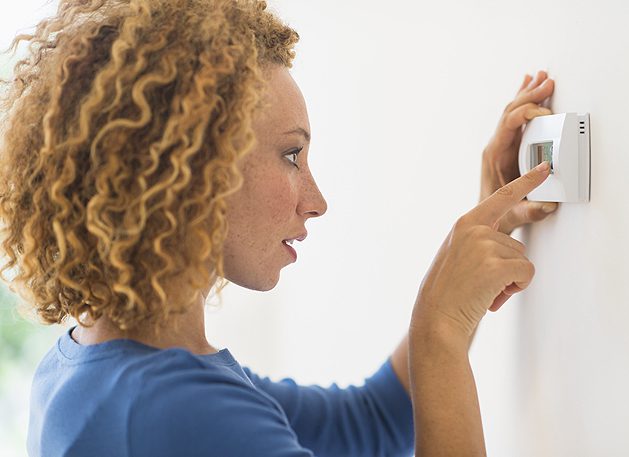 Adkins-Heating-and-Cooling-Woman-Changing-Thermostat